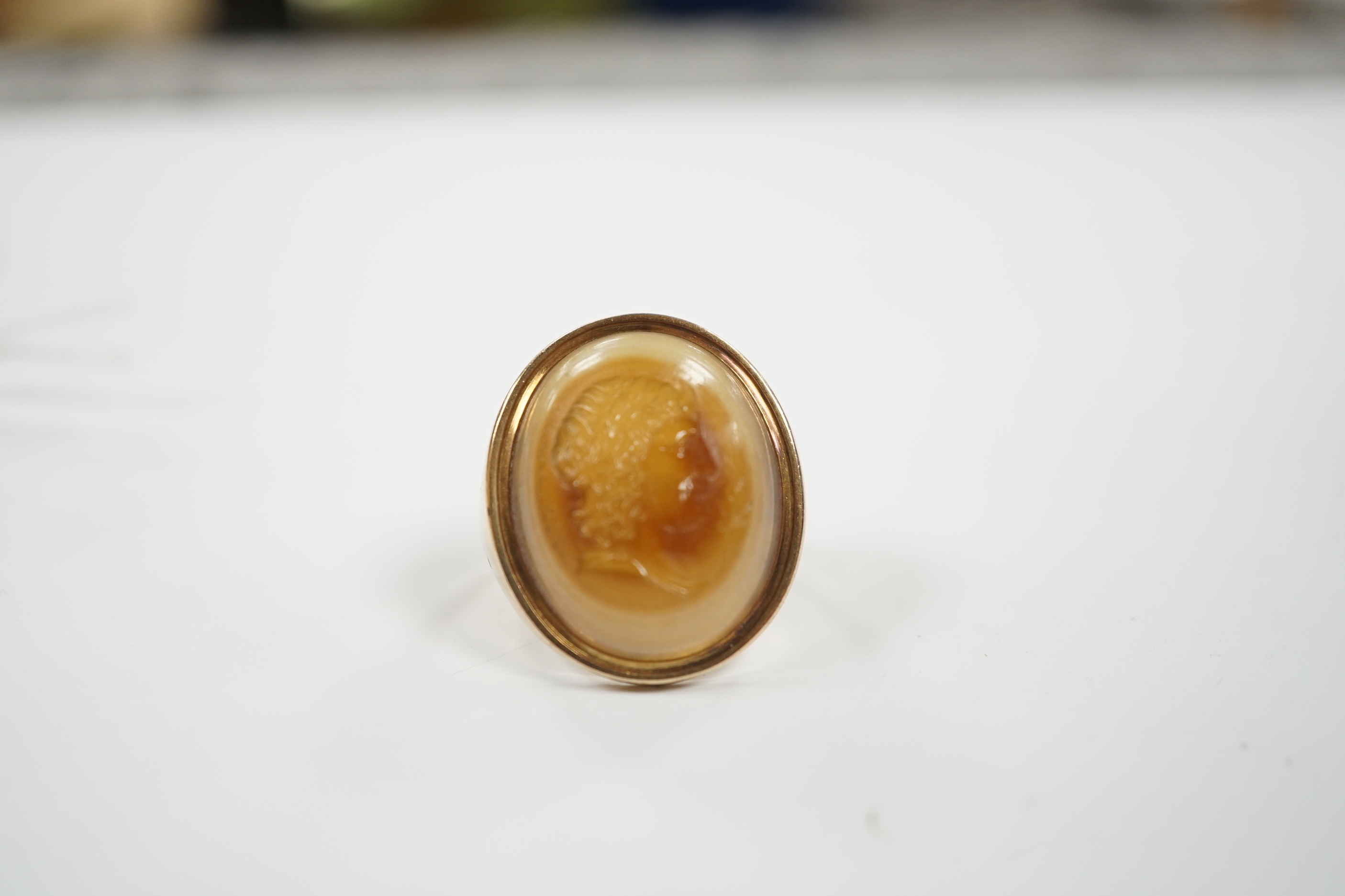 An early 20th century yellow metal and banded agate intaglio ring, carved with the head of a gentleman to sinister, size L, gross weight 8.1 grams.